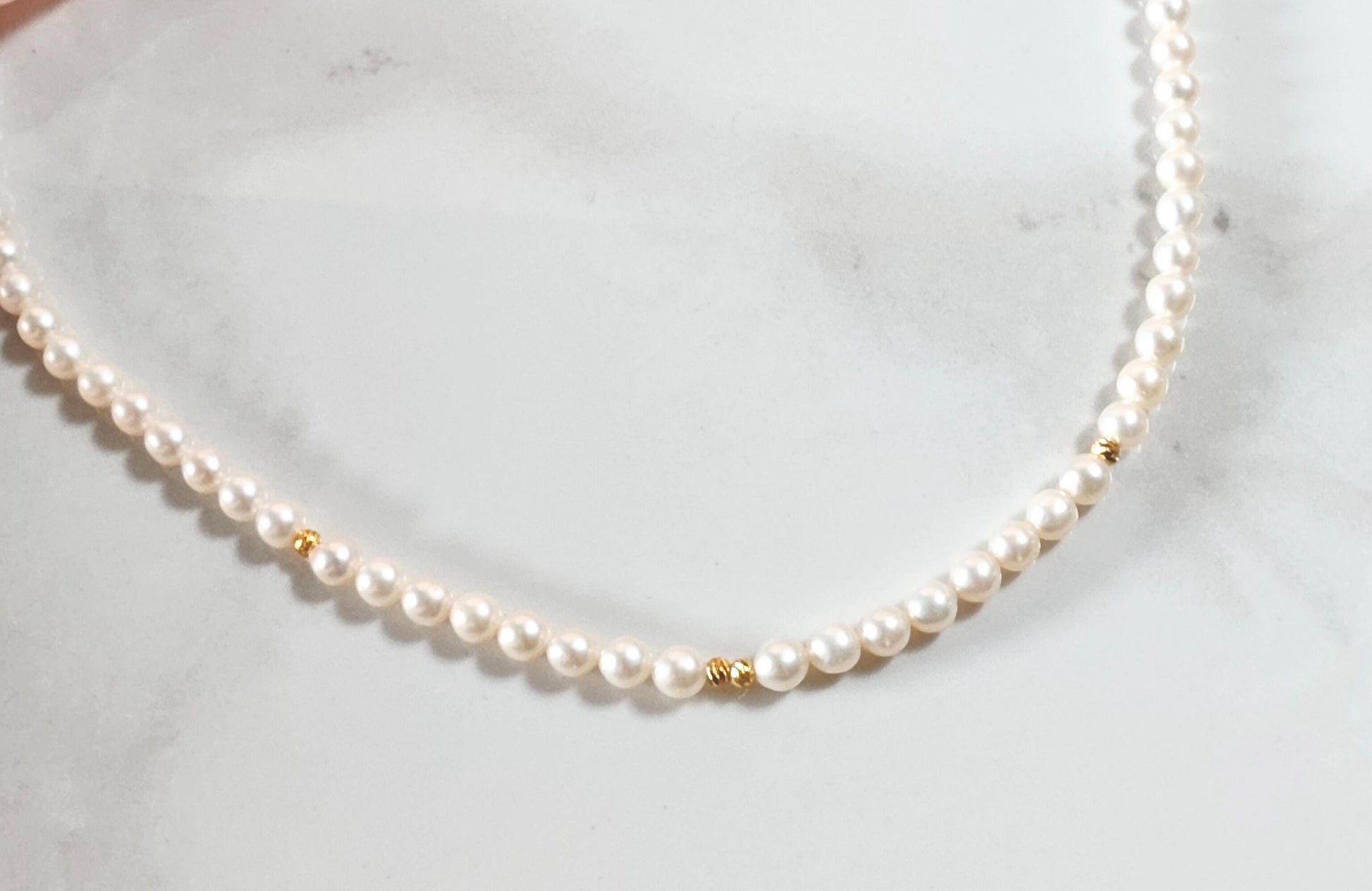 Pearl necklace with gold accents on a white marble surface