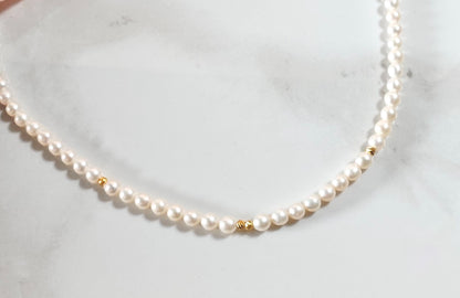 Pearl necklace with gold accents on a white marble surface