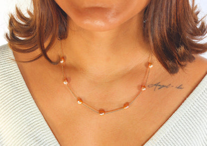 Necklace with orange beads worn by a person