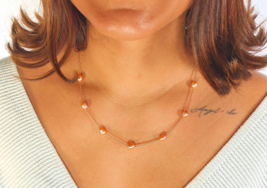 Necklace with orange beads worn by a person