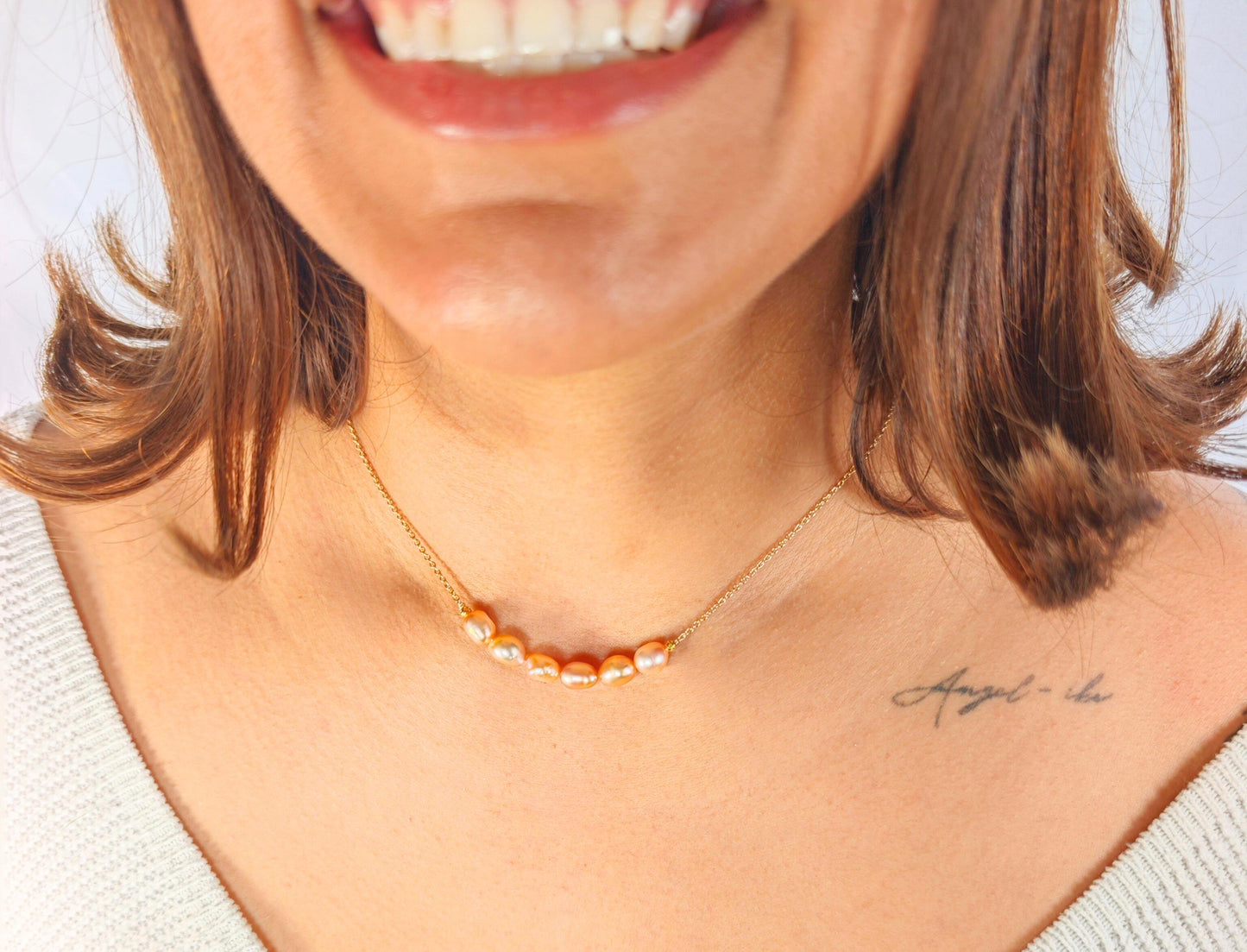 Close-up of a person wearing a gold necklace with a blurred background
