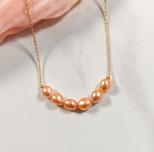 Necklace with pink pearls on a light pink fabric background