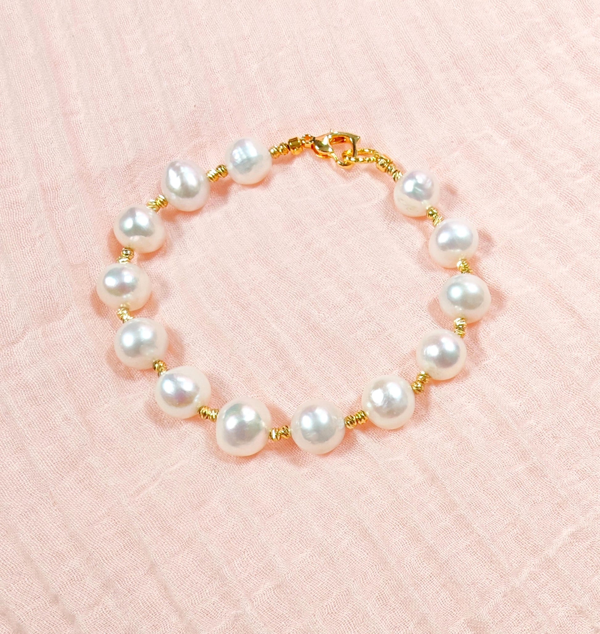 Pearl bracelet with gold accents on a pink background