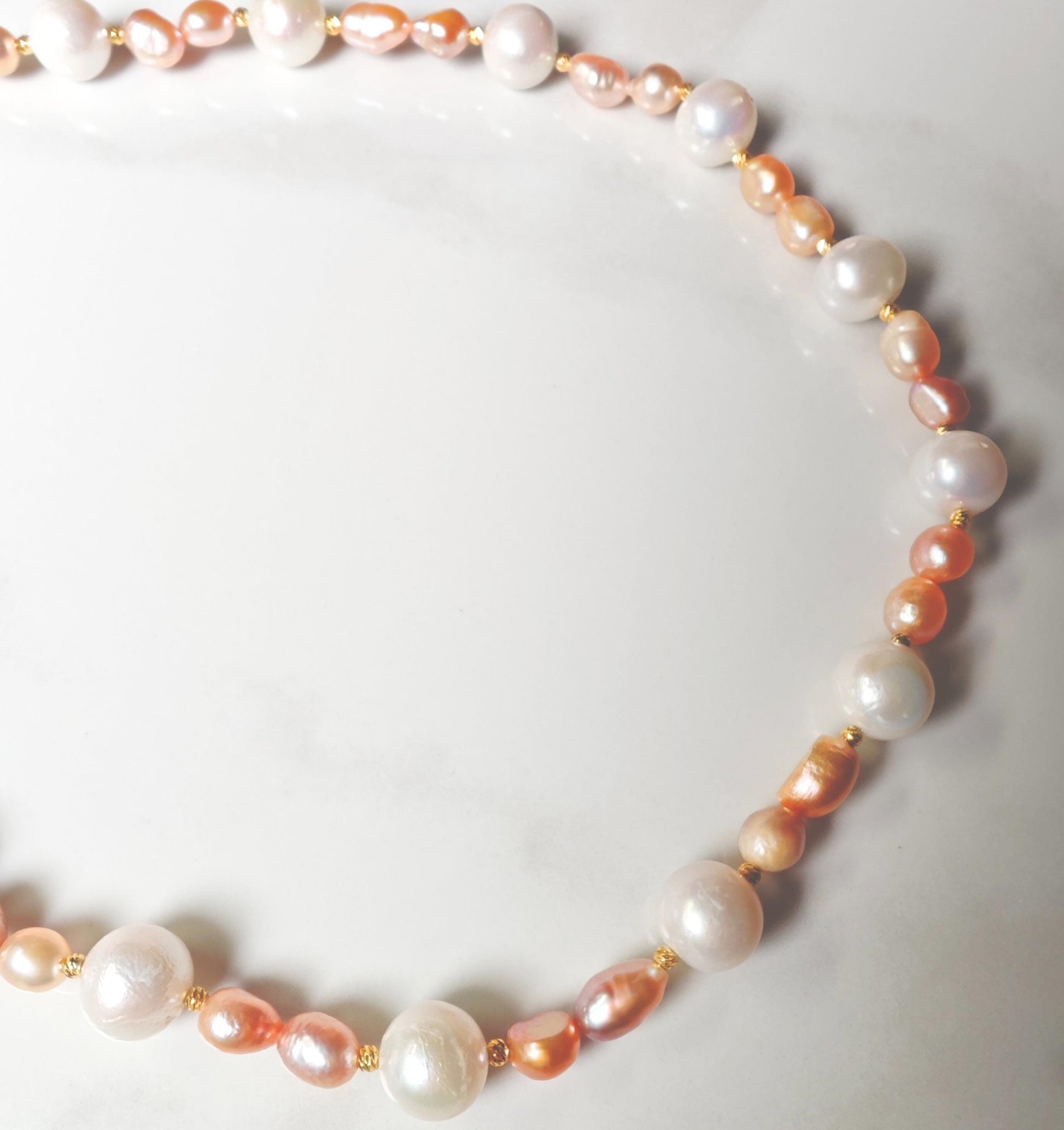 Necklace with pink and white pearls on a light gray background