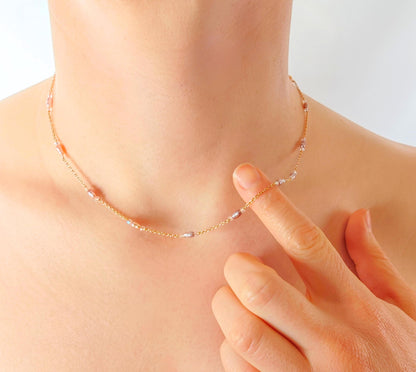 Necklace being worn on a person's neck with a hand adjusting it against a light background