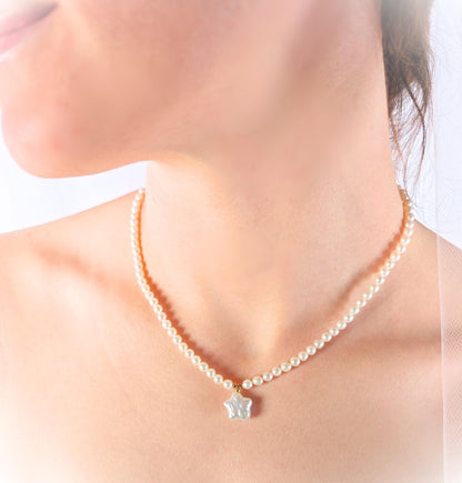 Pearl necklace with a star-shaped pendant on a person against a white background