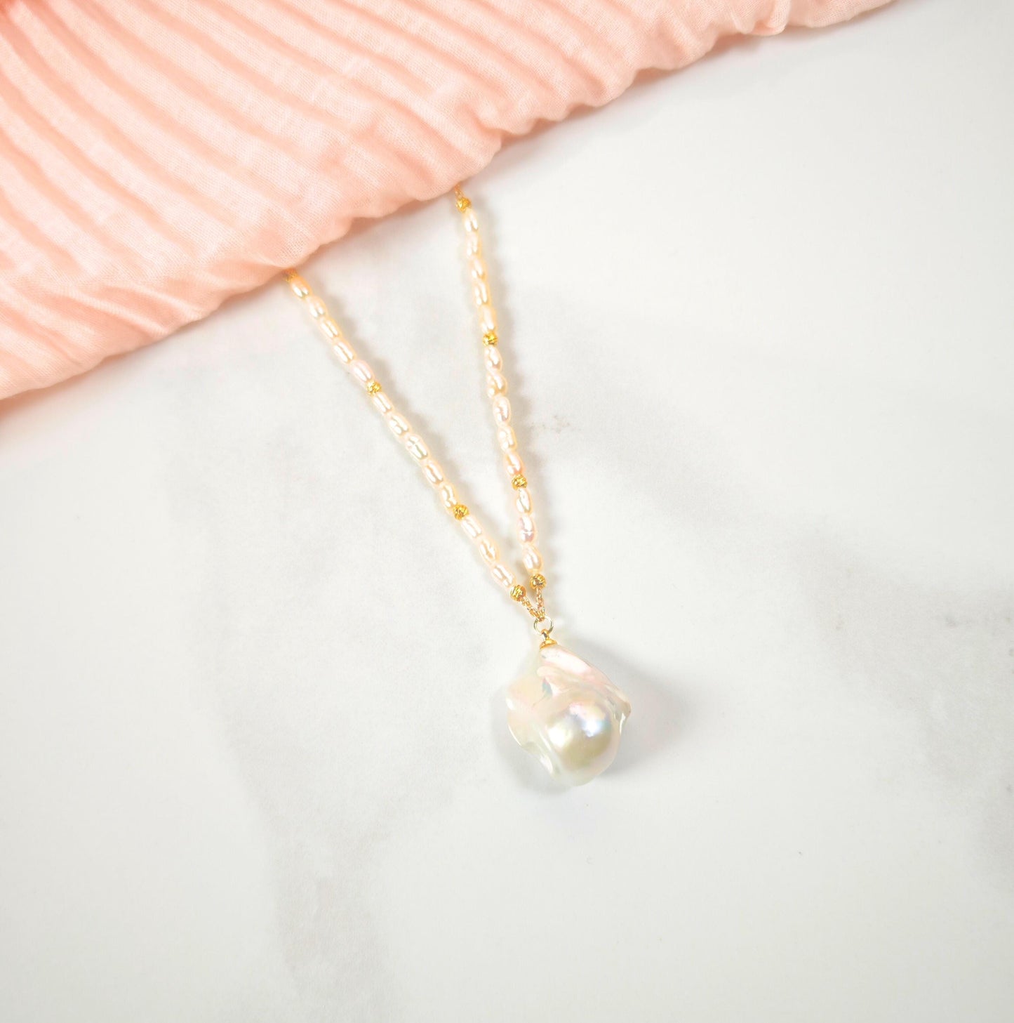 Pearl necklace on a light pink fabric background