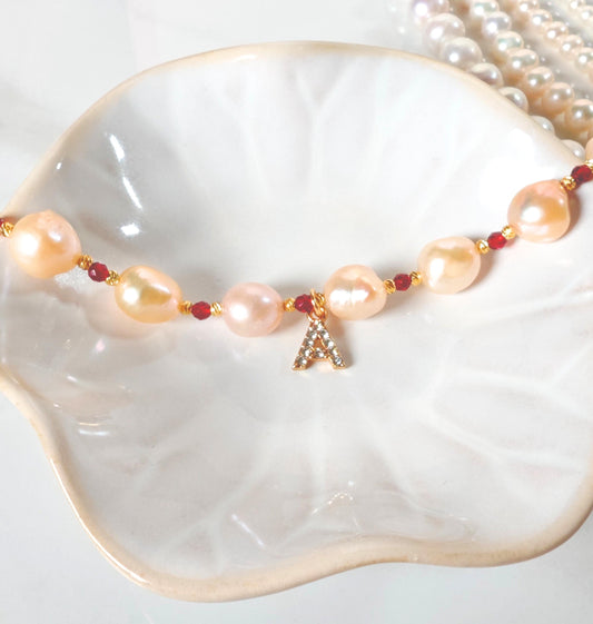 Pearl necklace with a letter 'A' charm on a white dish