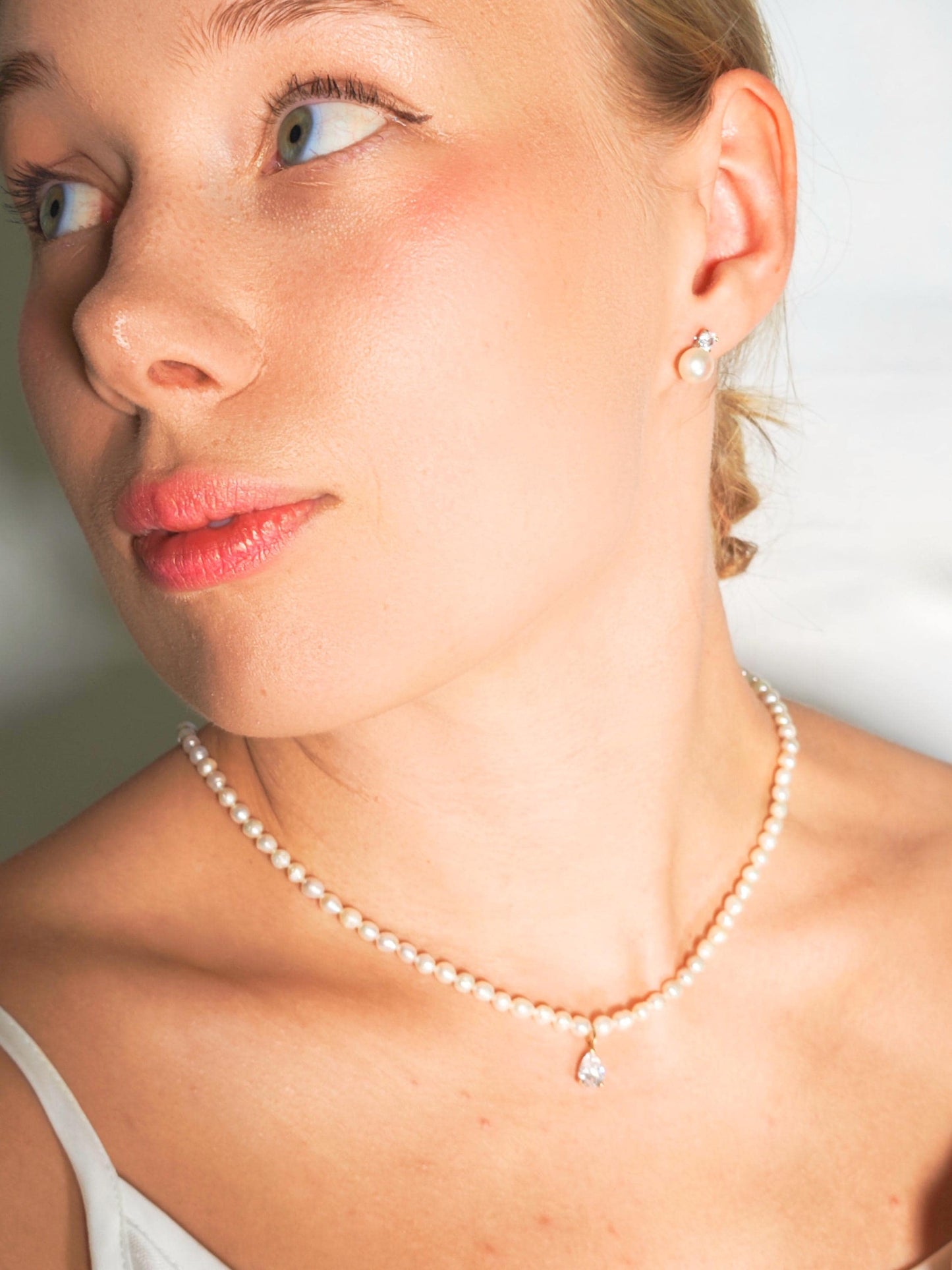 Close-up of a woman wearing a pearl necklace and earring.