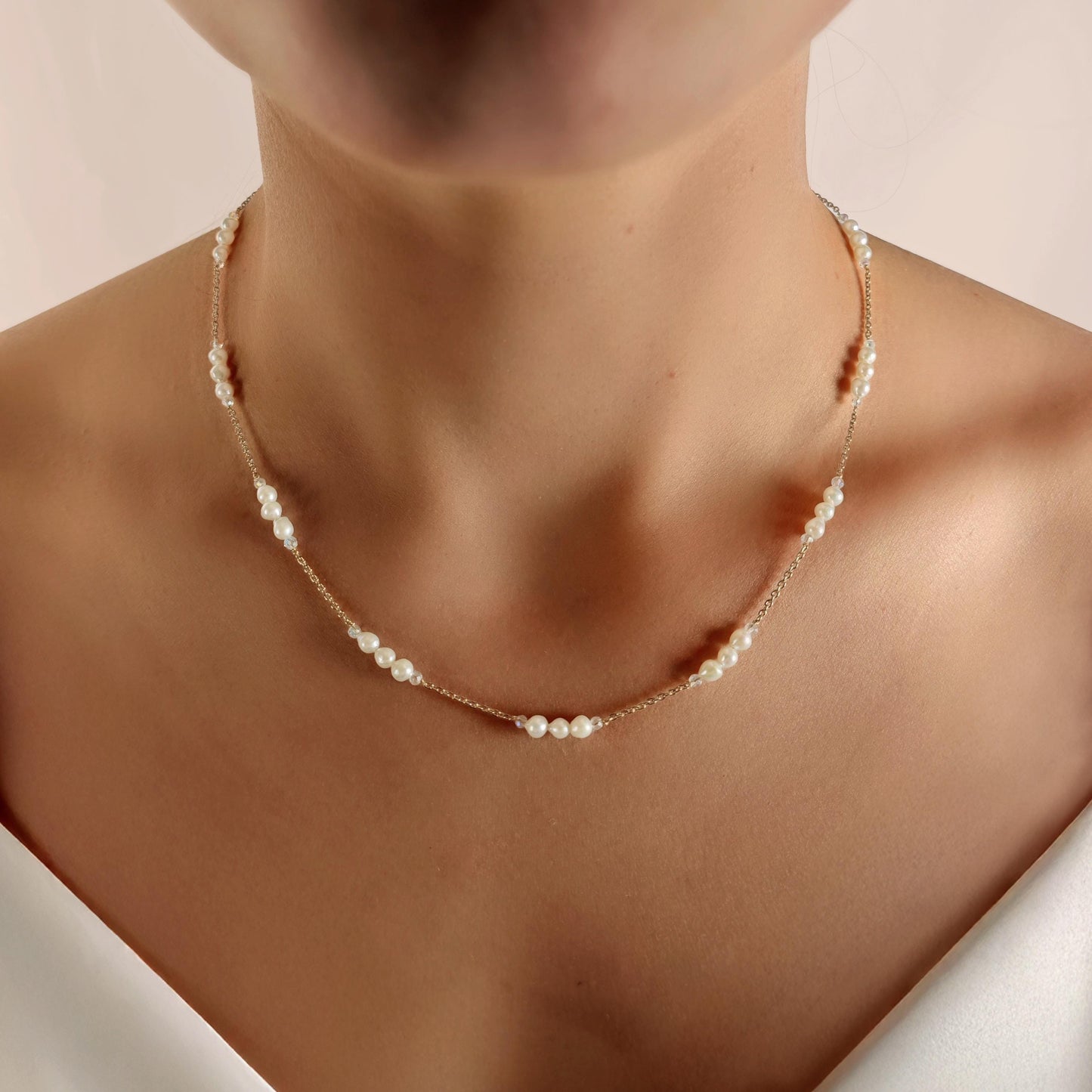 Pearl necklace on a person against a neutral background