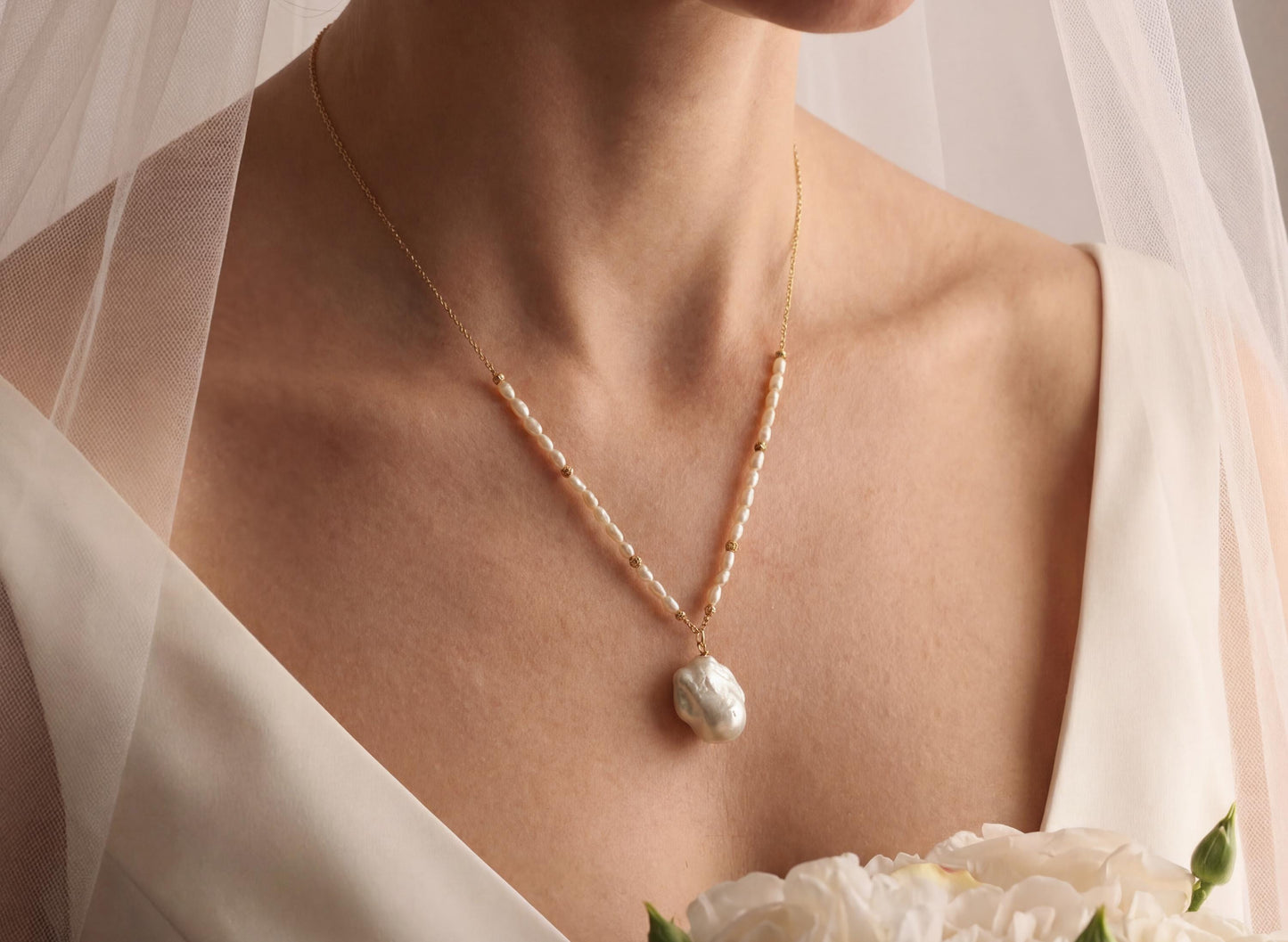 Pearl necklace worn by a person with a veil and flowers in the background