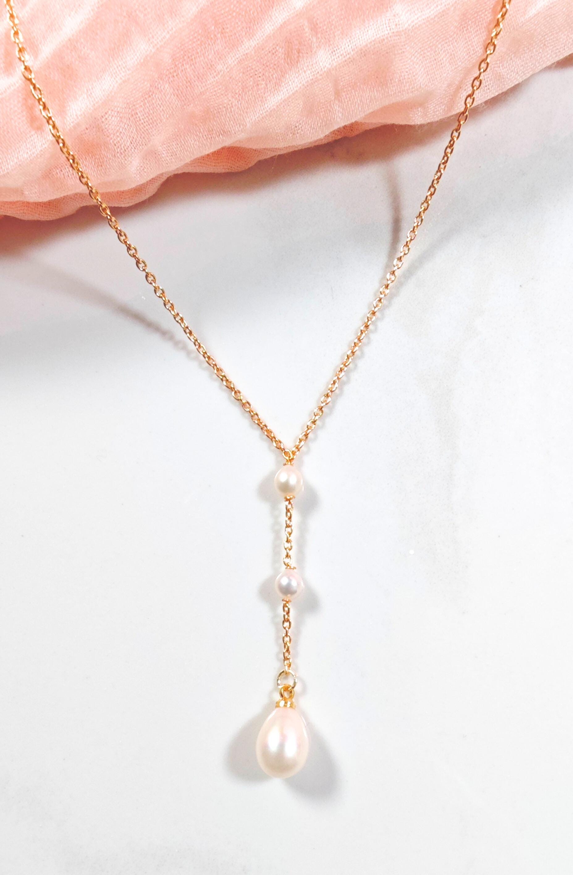 Pearl necklace on a gold chain with a soft pink fabric background