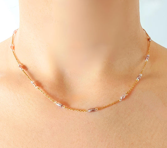 Necklace with small beads on a mannequin neck against a light blue background