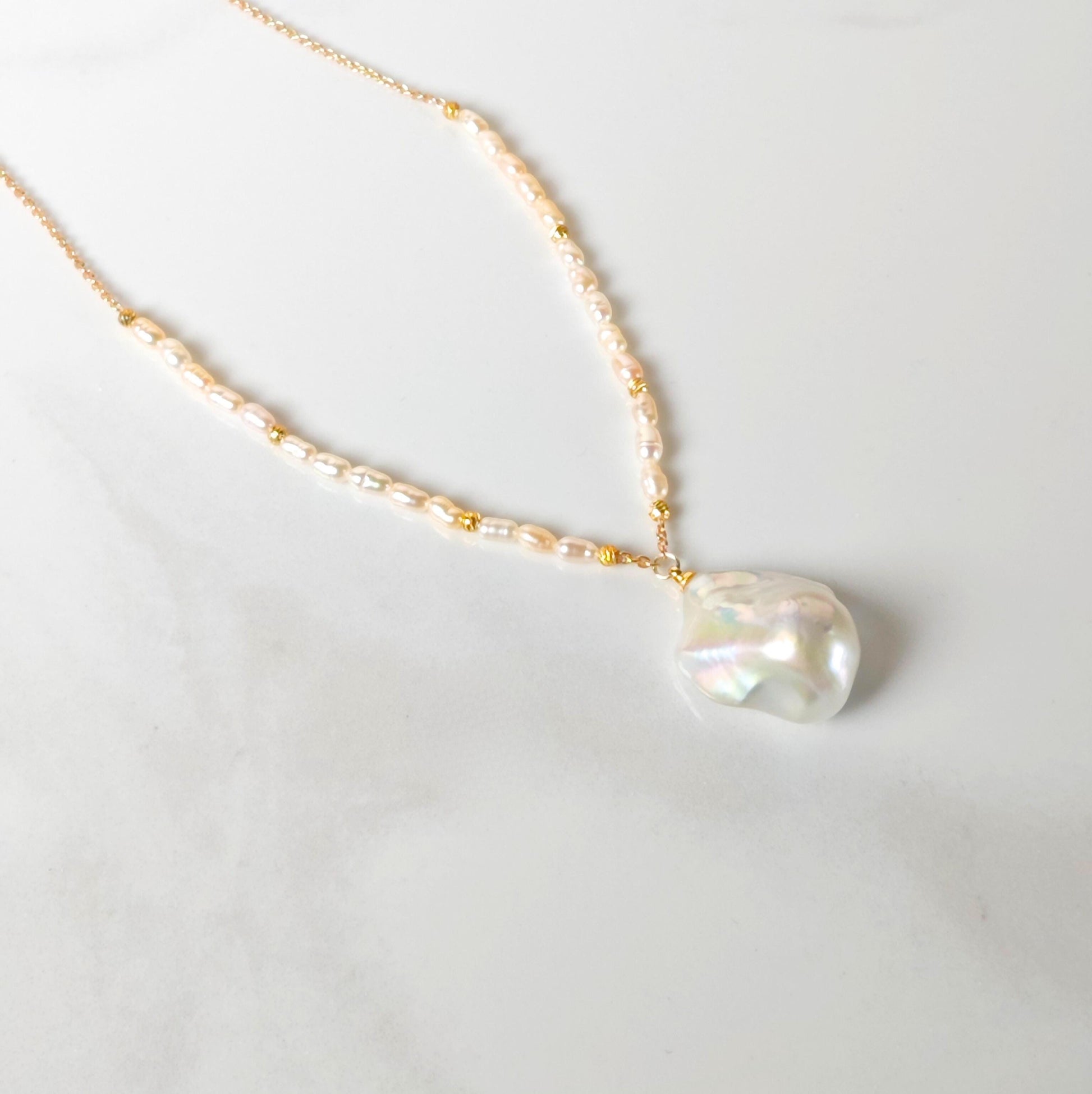 Pearl necklace with a gold chain on a light gray background