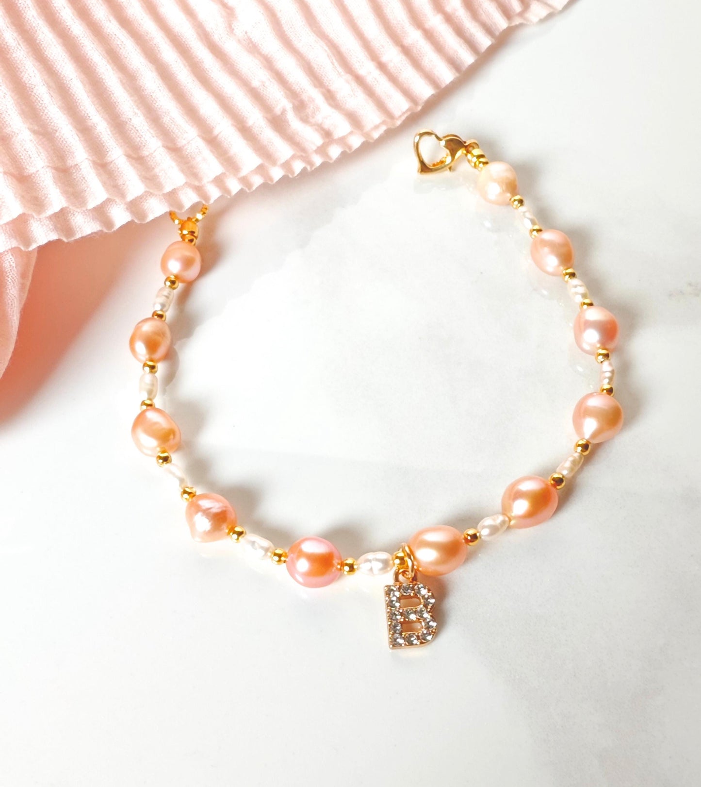 Pearl bracelet with a heart charm on a white background