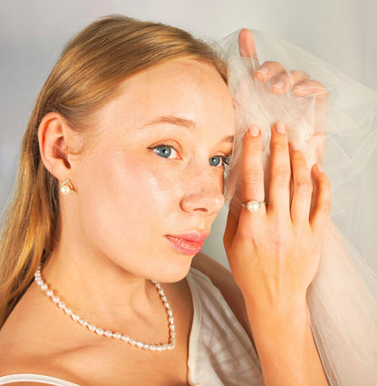 Woman holding a veil to her face with a neutral background