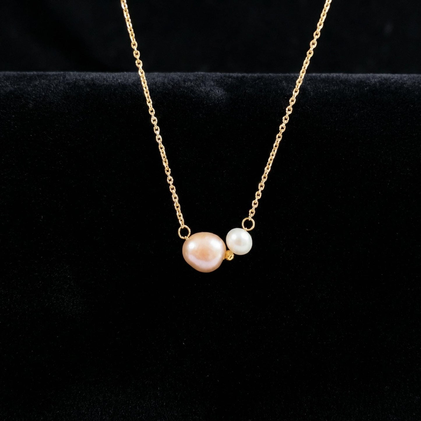 Gold necklace with two pearls on a black background