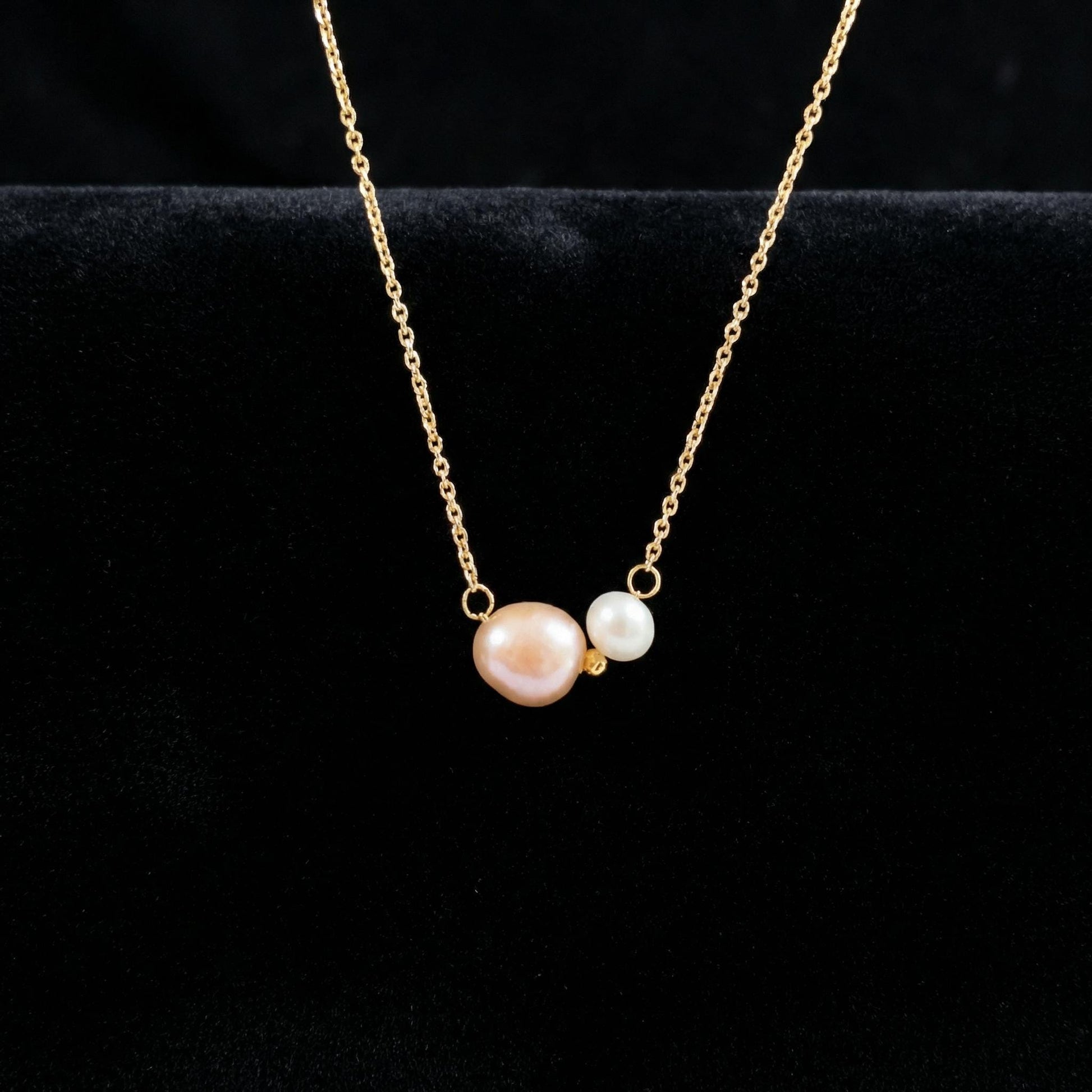 Gold necklace with two pearls on a black background