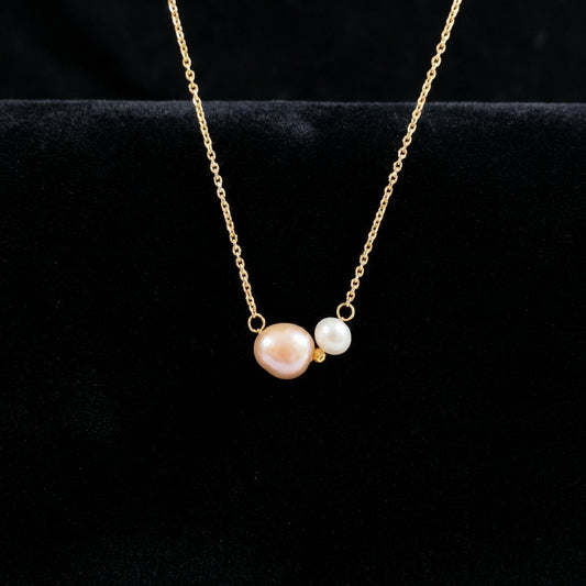Gold necklace with two pearls on a black background